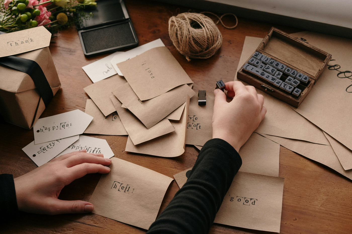 Person stamping envelopes with a wooden stamp on a wooden table.
